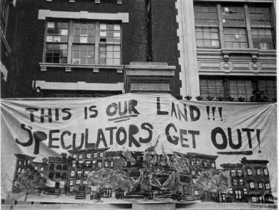 People holding up sign reading "The is our land!!! Speculators Get Out!"